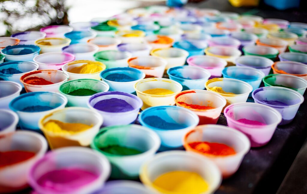 A vivid display of multicolored powders in plastic cups, ideal for arts and crafts projects.
